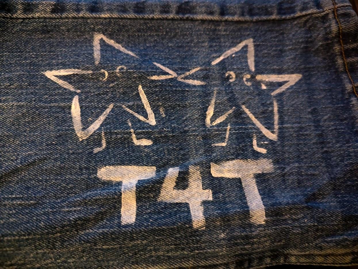 diy print on denim of two star-shaped characters holding hands, underneath the word 'T4T' is printed.